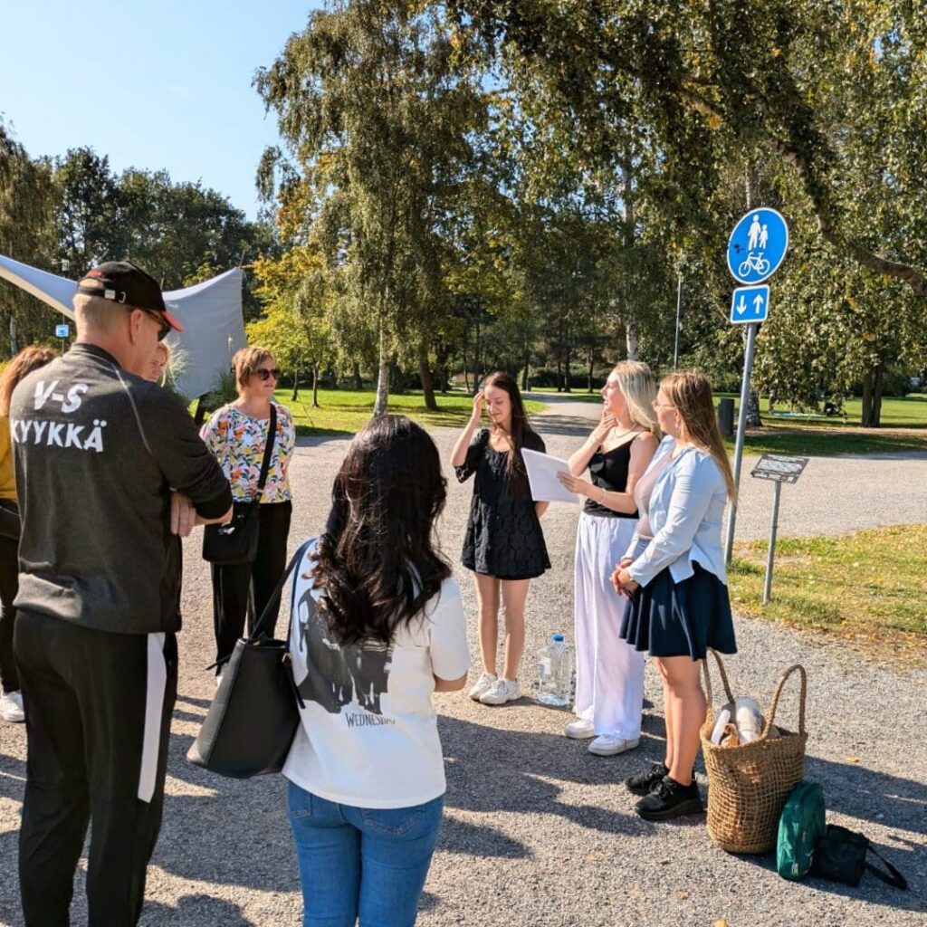 Matkailualan opiskelijat toteuttamassa ohjelmapalvelua asiakasryhmälle puistossa.